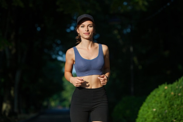 Jeune femme athlétique en tenue de sport faisant du jogging dans le parc Fitness et mode de vie sain