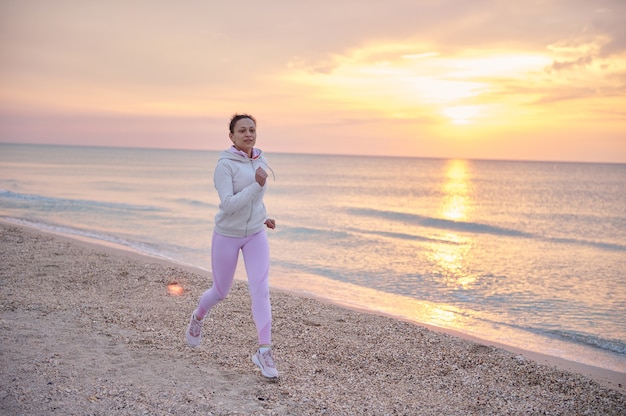 Jeune Femme Athlétique En Tenue De Sport Rose Effectuant Un Jogging Matinal Le Long Du Littoral De La Mer