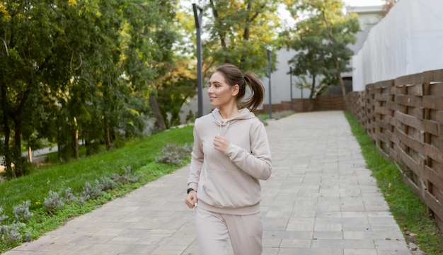 Jeune femme athlétique en vêtements de sport pratiquant le jogging matinal à l'extérieur dans le parc