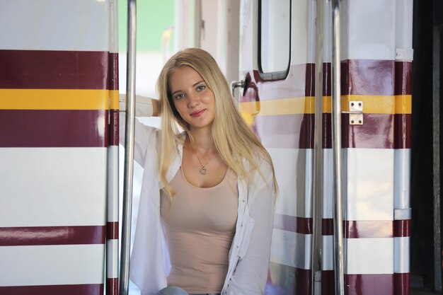 Jeune femme attendant dans un train vintage, détendue et insouciante sur le quai de la gare