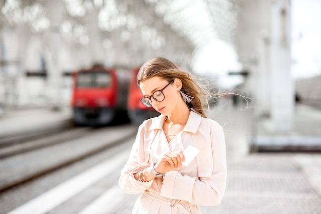 Jeune femme attendant le train debout tristement sur le quai de la gare