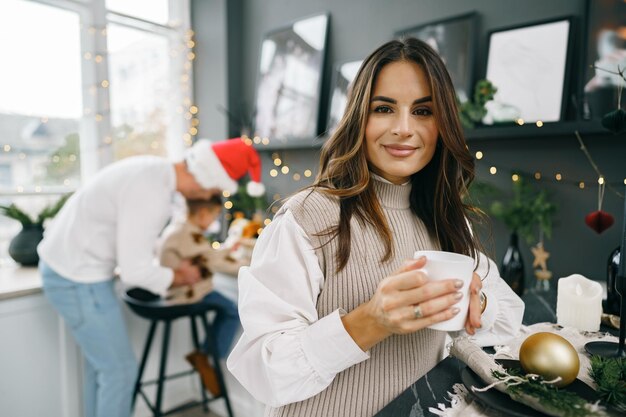 Une jeune femme attirante boit du thé dans la cuisine pour Noël