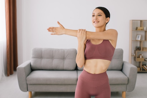 Jeune femme attirante et en bonne santé faisant des exercices tout en se reposant à la maison