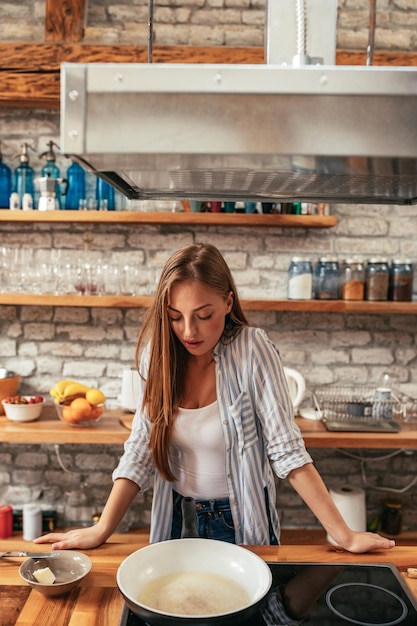 Une jeune femme attirante faisant cuire dans sa cuisine