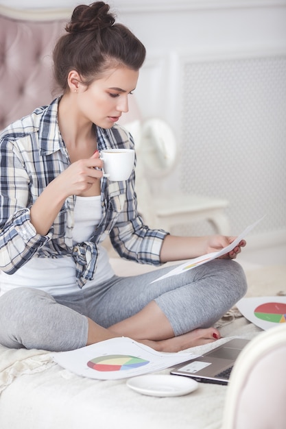 Jeune femme attirante faisant cuire la salade à l'intérieur à la cuisine