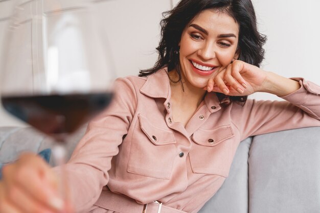 Jeune femme attirante regardant le verre de vin et souriant