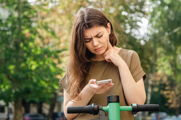 Jeune femme attirante avec un scooter électrique de location un jour ensoleillé