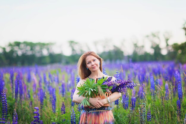 Jeune femme attirante tenant un panier plein de fleurs de lupin