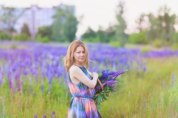 Jeune femme attirante tenant un panier plein de fleurs de lupin