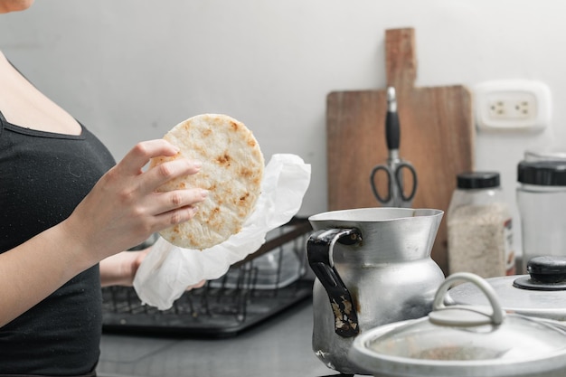 Jeune femme attrapant un arepa blanc pour le chauffer dans sa cuisine fille préparant le petit déjeuner colombien