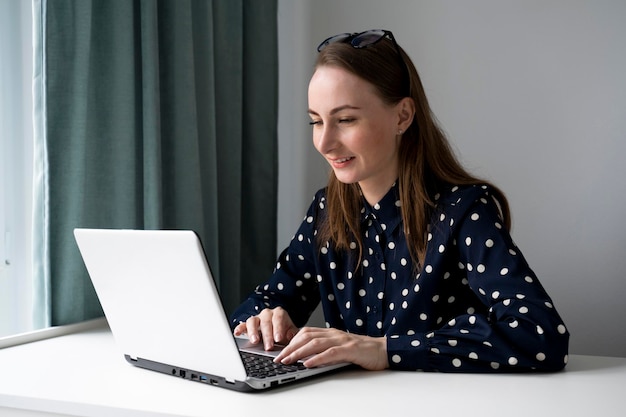 Photo une jeune femme attrayante utilise un ordinateur portable tout en faisant ses devoirs en utilisant une connexion internet