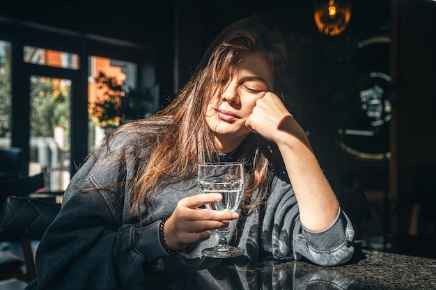 Une jeune femme attrayante avec un verre d'eau dans un café