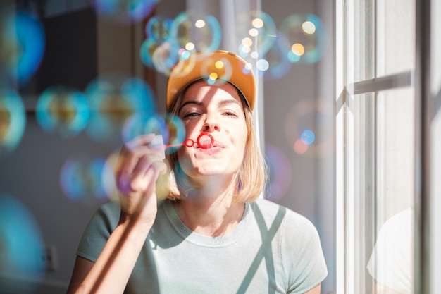 Jeune femme au bonnet jaune soufflant des bulles de savon Concept de divertissement de style de vie amusant