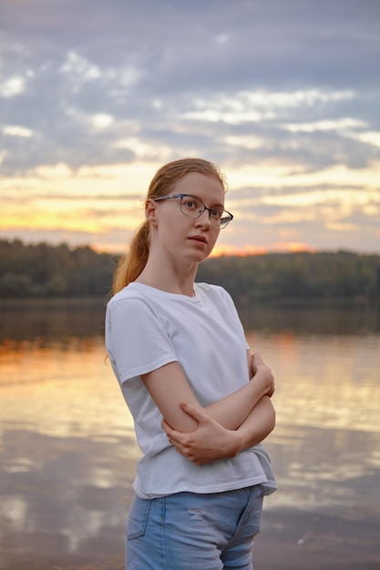 Jeune femme au bord du lac au coucher du soleil