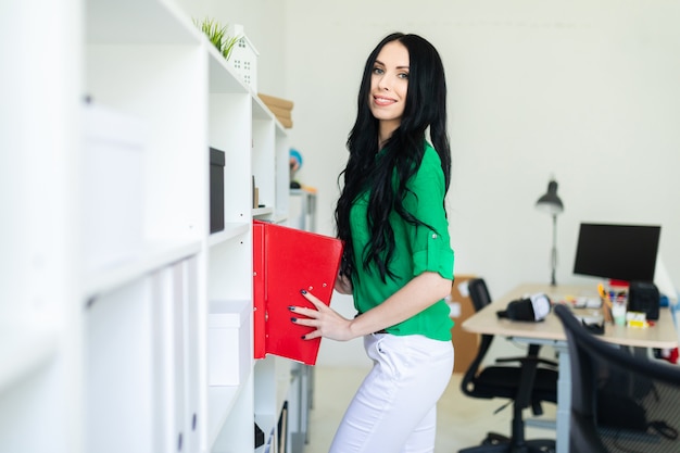 Une jeune femme au bureau sort des dossiers avec des documents.