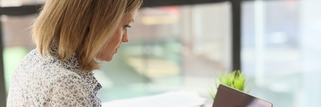 Une jeune femme au bureau tape sur un clavier d'ordinateur portable un entrepreneur en heures supplémentaires en gros plan