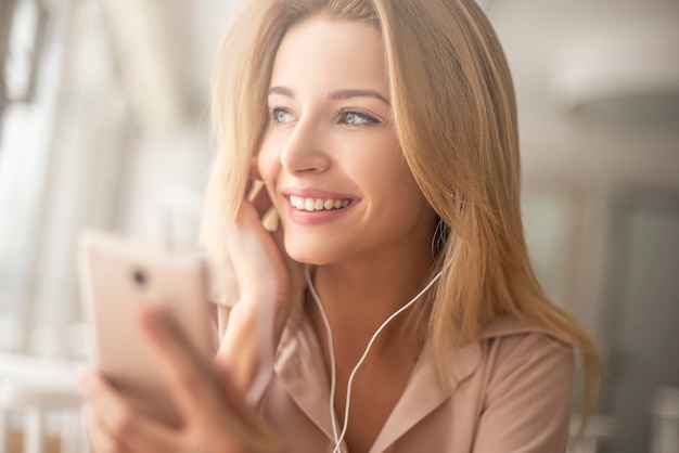 Jeune femme au café assis à écouter de la musique en regardant par la fenêtre en gros plan de rêve