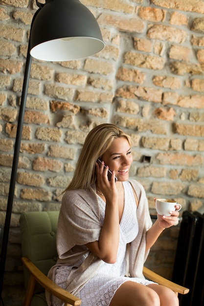 Jeune femme au café avec téléphone portable