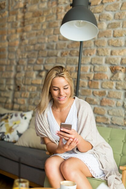 Jeune femme au café avec téléphone portable