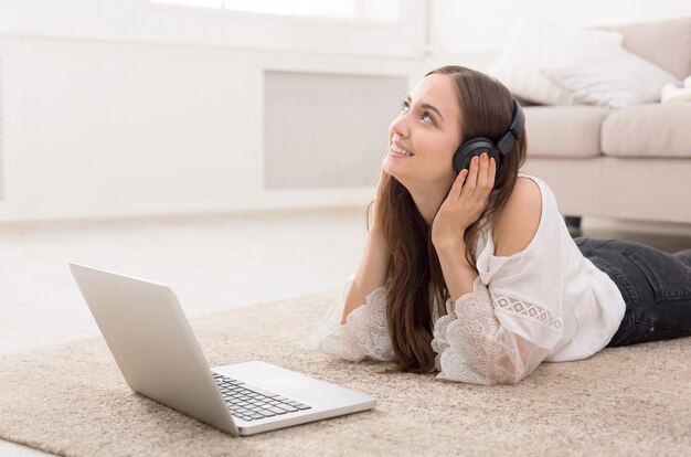 Jeune femme au casque en ligne sur ordinateur portable