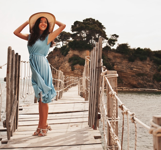 Photo jeune femme au chapeau d'été posant sur le pont