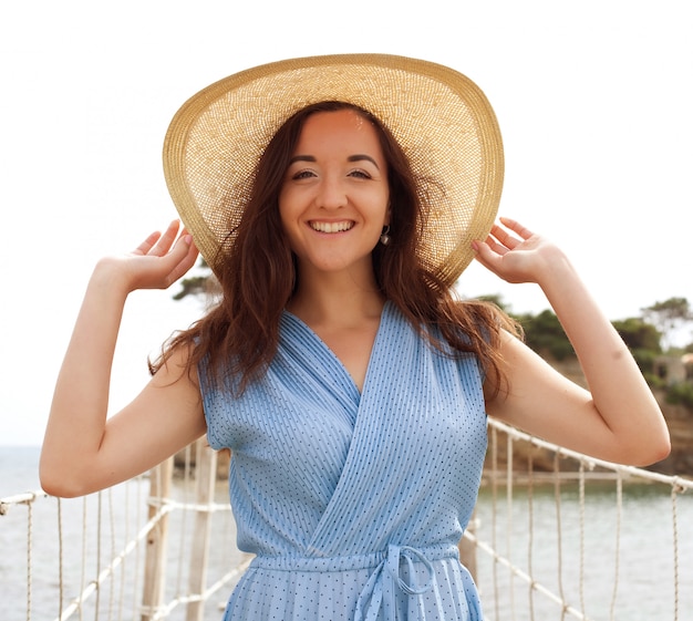 Jeune femme au chapeau d'été posant sur le pont