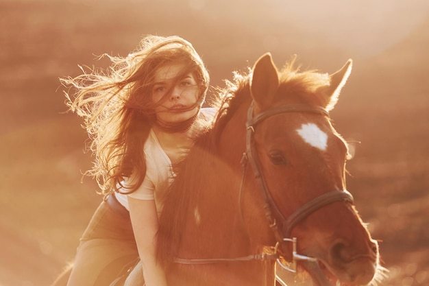 Jeune femme au chapeau de protection avec son cheval dans le domaine de l'agriculture à la journée ensoleillée