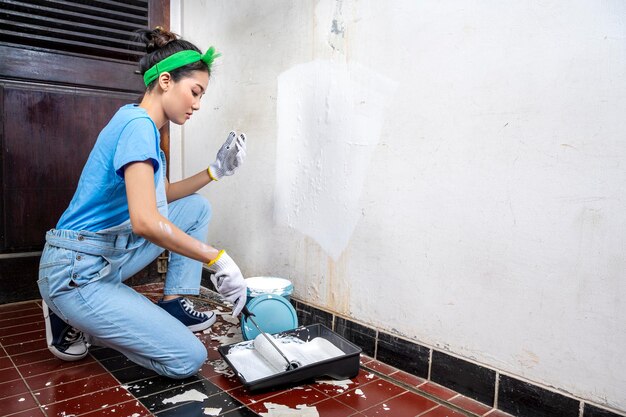 Jeune femme au foyer asiatique en gant à l'aide d'un pinceau à peinture