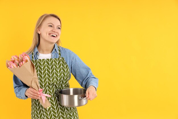 Jeune femme au foyer avec bouquet de fleurs sur fond jaune