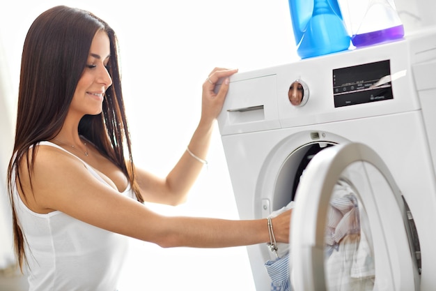 jeune femme au foyer avec buanderie à côté de la machine à laver