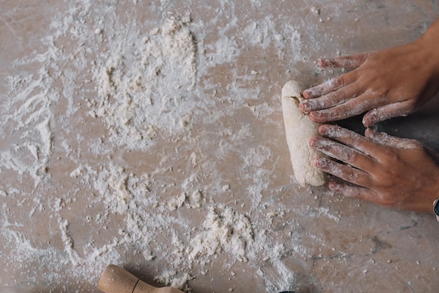 Jeune femme au foyer dans un tablier pétrit la pâte avec ses mains