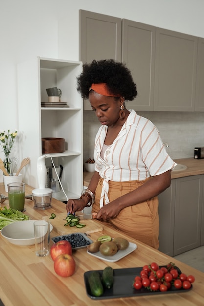 Photo jeune femme au foyer faisant cuire une salade de légumes dans la cuisine