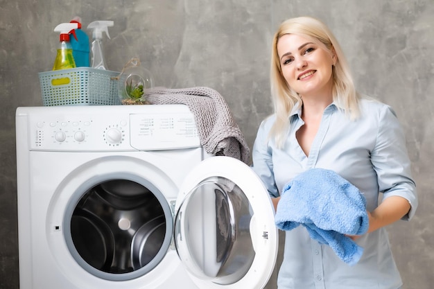 Une jeune femme au foyer avec machine à laver et vêtements. Jour de lessive.