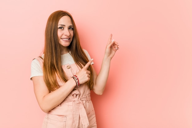 Jeune femme au gingembre avec des taches de rousseur choqué pointant avec l'index vers un espace de copie.