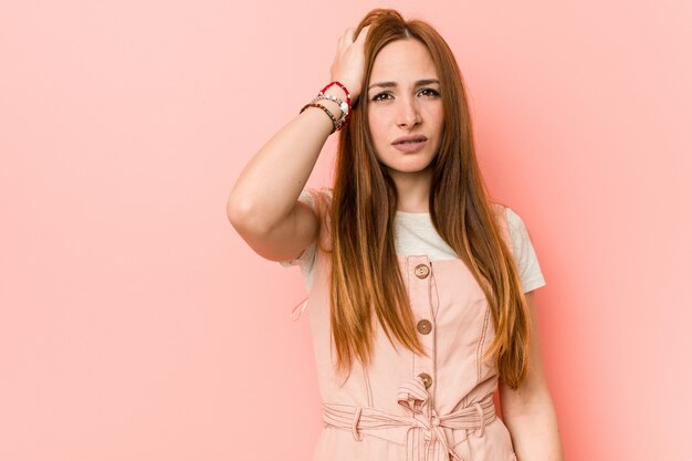 Jeune femme au gingembre avec des taches de rousseur fatiguée et très endormie en gardant la main sur la tête.