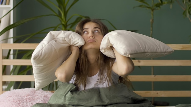 Photo une jeune femme au lit essaie de se reposer irritée par l'insomnie des voisins bruyants