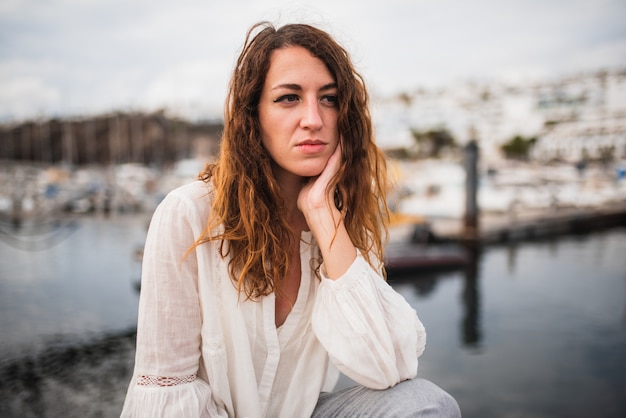 Jeune femme au visage pensif assis au bord de la mer.