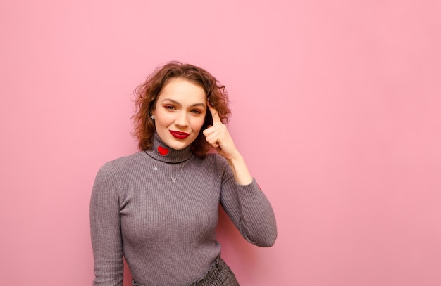 Jeune femme au visage pensif isolé sur fond rose