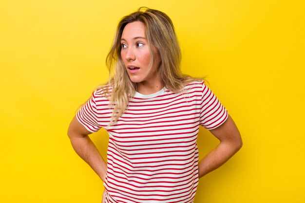 Jeune femme australienne isolée regarde de côté souriant, gai et agréable.