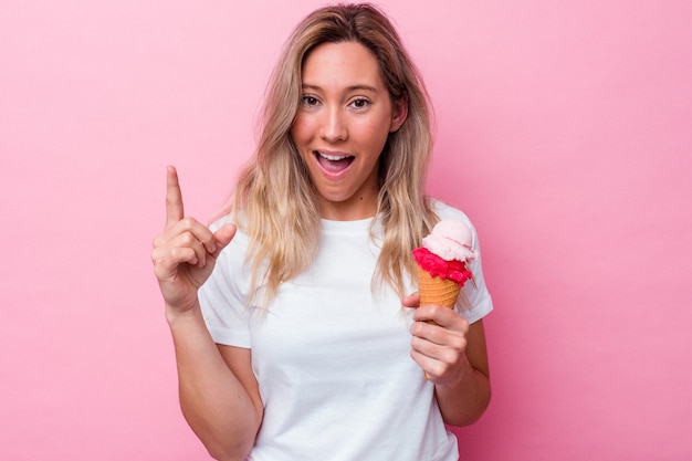 Jeune femme australienne tenant une glace isolée sur fond rose ayant une idée, un concept d'inspiration.