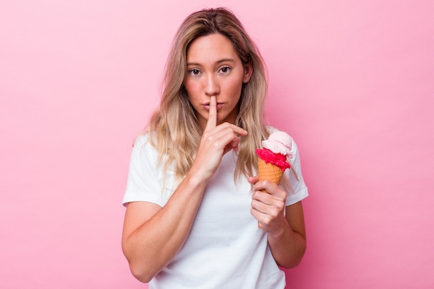 Jeune femme australienne tenant une glace isolée sur fond rose gardant un secret ou demandant le silence.