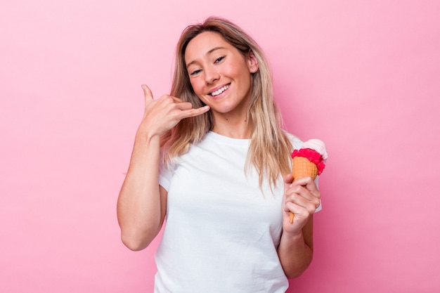 Jeune femme australienne tenant une glace isolée sur fond rose montrant un geste d'appel de téléphone portable avec les doigts.