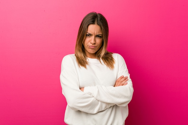 Jeune femme authentique charismatique de personnes réelles contre un mur fronçant les sourcils de mécontentement, garde les bras croisés.