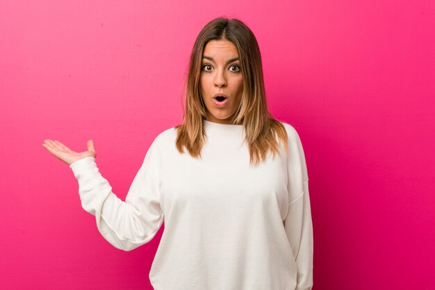 Jeune femme authentique, de vraies personnes charismatiques contre un mur, impressionnée par l'espace réservé à la copie.