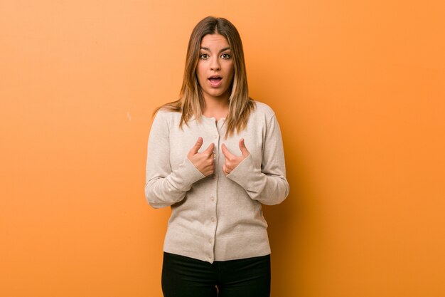 Jeune femme authentique de vraies personnes charismatiques contre un mur surprise en pointant du doigt, souriant largement.