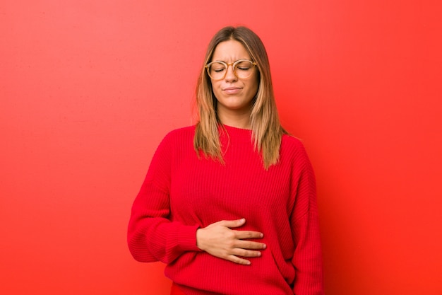 Photo jeune femme authentique de vraies personnes charismatiques contre un mur touche le ventre, sourit doucement