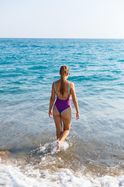 Jeune femme aux cheveux blonds posant et se reposant sur l'océan. Un beau corps athlétique d'un touriste sur l'île. Mise au point sélective.