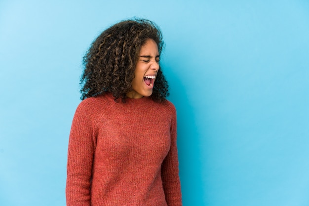 Jeune femme aux cheveux bouclés afro-américaine criant vers un espace vide