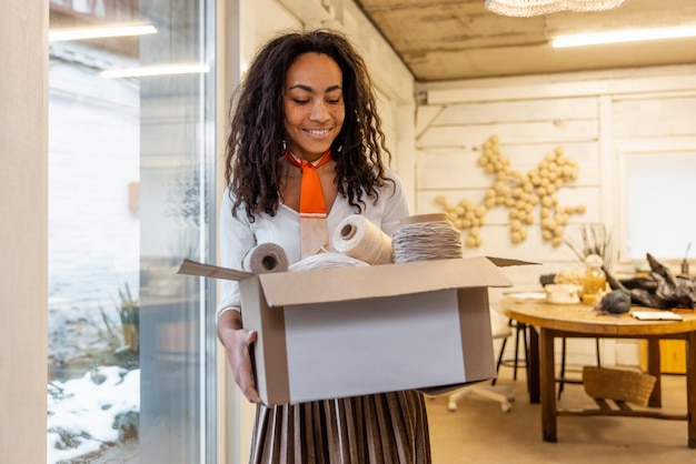 Jeune femme aux cheveux bouclés avec un carton dans les mains