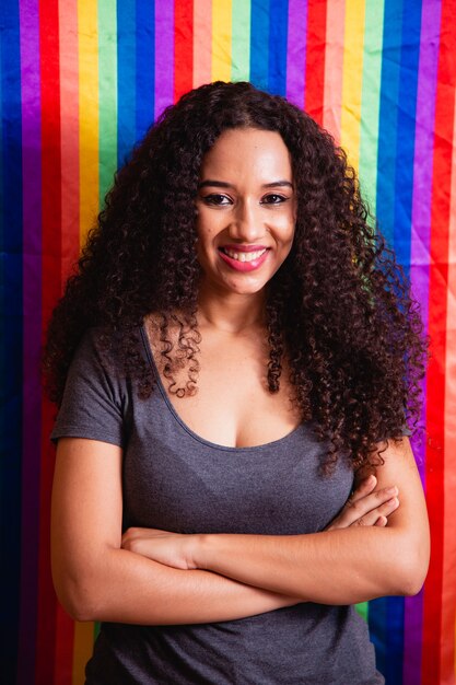 Jeune femme aux cheveux bouclés couvrant avec un drapeau de fierté lgbt. Seul. Une. Garder le poing levé, couvrant le drapeau LGBT. Drapeau LGBT+ sur fond jaune.